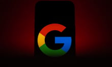 A phone in ominous red lighting displaying a Google logo.