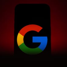 A phone in ominous red lighting displaying a Google logo.