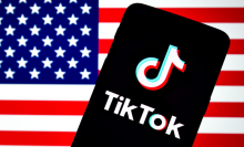 The TikTok logo seen displayed on a smartphone with an American flag in the background.