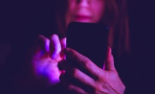 A woman using smartphone at night under colorful LED lights