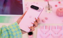 A phone with rose pink painted nails holds a rose pink Pixel 9 Pro.