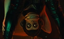 A creepy toy monkey stares out from behind a woman's spread legs. 