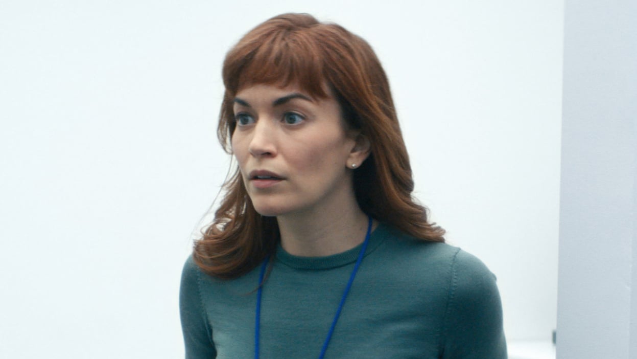 A woman stands in a white room.