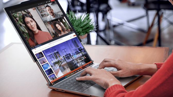 A person types on a laptop. It's screen is extended by a second screen that has been pulled out from the top of the original screen.  