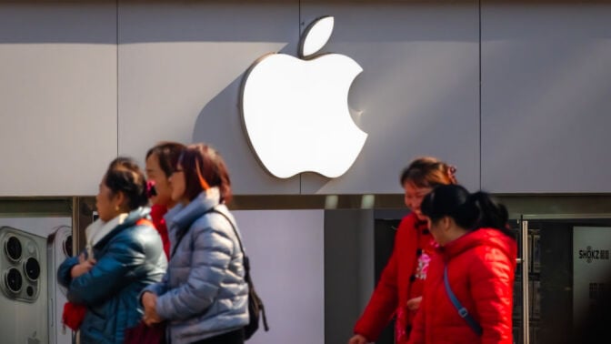 People walking past an Apple logo on a wall in China