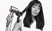 women uses dyson supersonic with flyaway smoother attachment to blow dry her hair