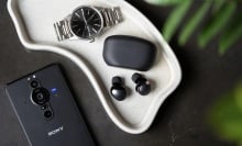 black sony wf-1000xm5 earbuds on tray next to watch and sony phone