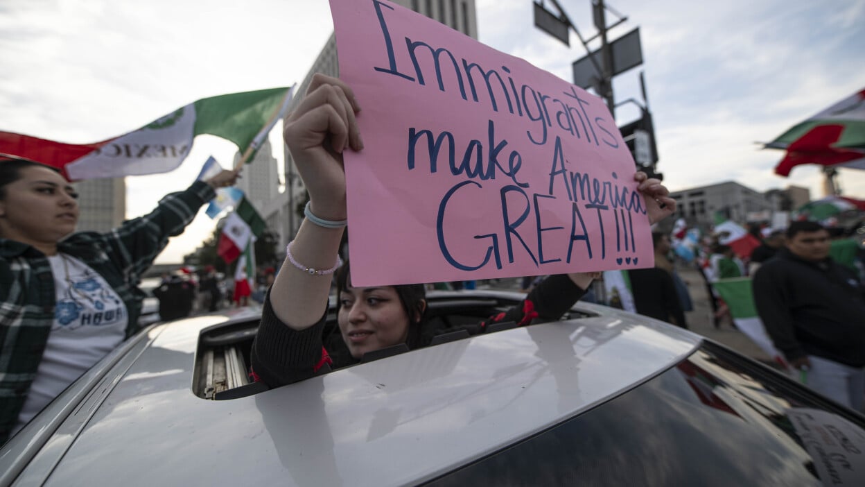 A protester holds up a sign that reads "Immigrants Make America Great!"