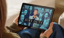 A person holiding an Amazon Fire HD 10 tablet showing the show Jury Duty