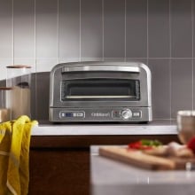 the cuisinart indoor pizza oven sits on a kitchen countertop with ingredients around it