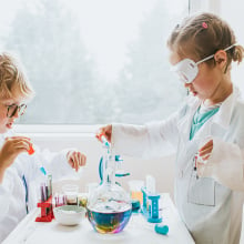 A girl and boy play with a lab science kit.