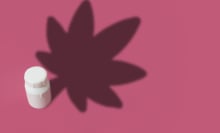 Illustration of a medicine bottle that casts a shadow of a marijuana leaf on a pink background with copy space