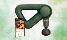 A green Theragun Prime massage gun next to a smartphone displaying the Therabody app.