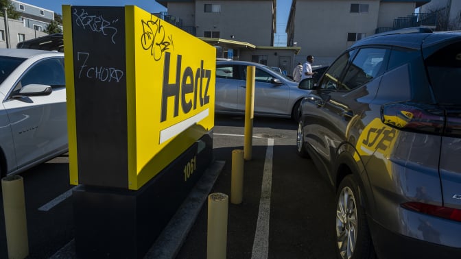 a hertz sign in between two parked cars