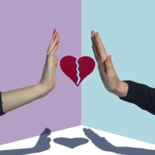 Two people hold up outstretched palms with a broken heart in between their hands.