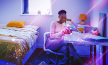 A young women in her dorm room surrounded by tech. 