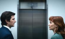 A man and a woman facing each other in front of an elevator.