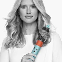 person styling hair with volumizing round brush attachment of dyson airwrap