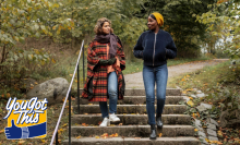 Two people wearing fall clothes walking down stairs in park