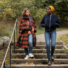 Two people wearing fall clothes walking down stairs in park