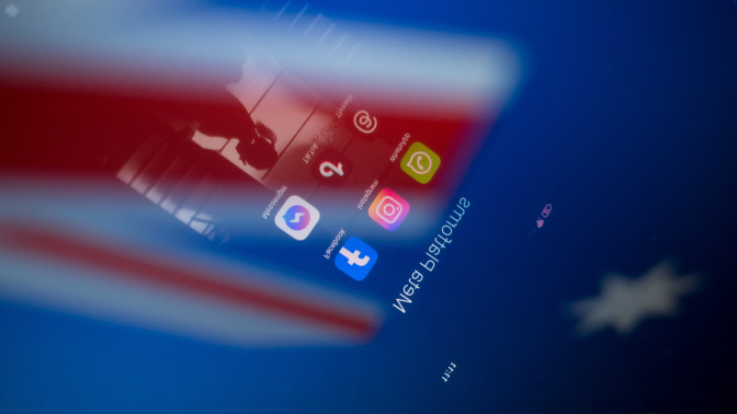 Social network logos display on a smartphone screen and the Australian flag appears on a computer screen in this photo illustration in Athens, Greece, on November 21, 2024. The Australian government proposes a ban on social media for all citizens under 16. Citing the success of recently introduced restrictions on mobile phones in Australian schools, the prime minister announces the ban by declaring that it is doing harm to children and he is calling time on it.