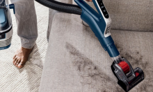 close up of person vacuuming couch cushion with shark stratos vacuum