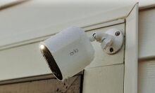 an arlo spotlight security camera affixed to the side of a house