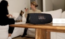 jbl charge 5 speaker on coffee table in front of two women and dog sitting on living room couch