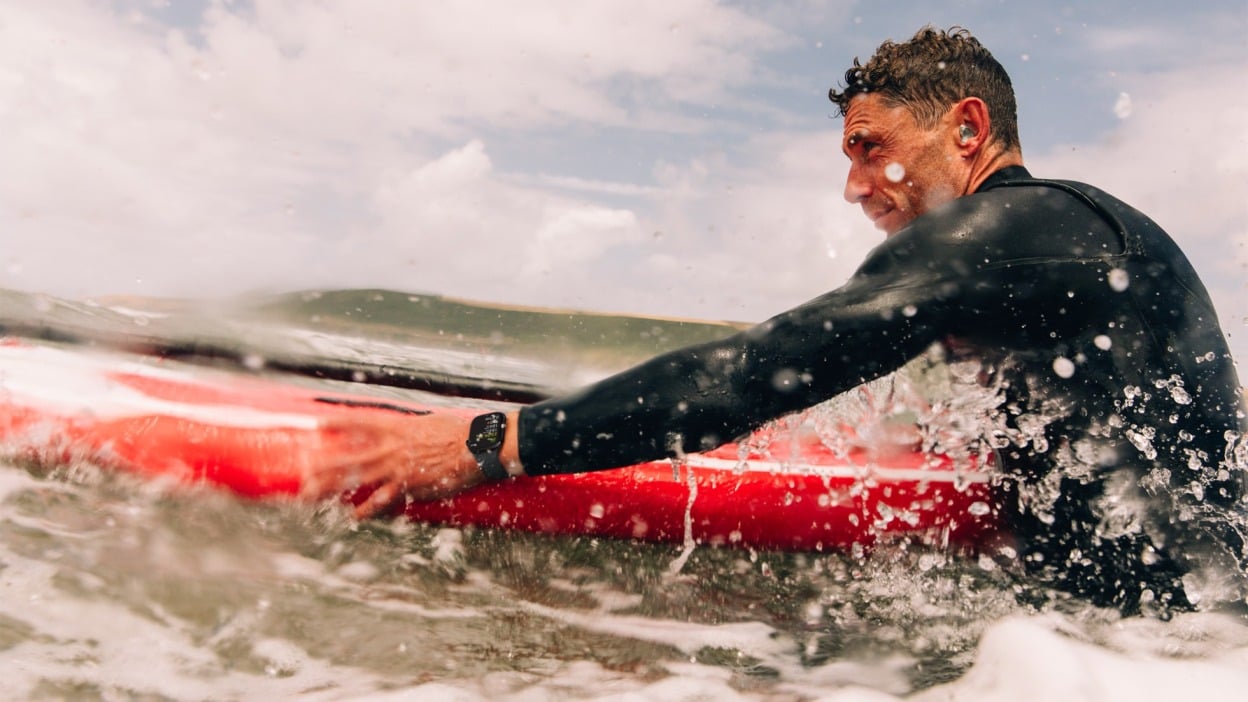 man on surfboard in ocean wearing apple watch