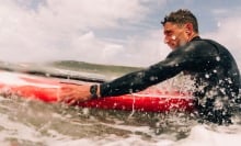 man on surfboard in ocean wearing apple watch