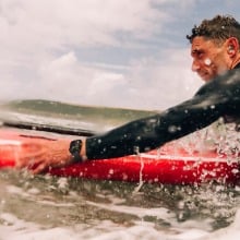 man on surfboard in ocean wearing apple watch