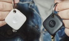 person holding a key in each hand with black and white tile tracker on key rings