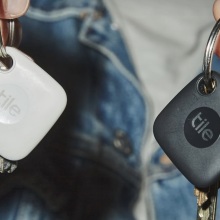 person holding a key in each hand with black and white tile tracker on key rings