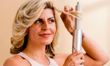 a close-up of a woman using a shark flexstyle to curl her hair