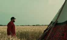 Mo Amer stands in a field beside a tent in the show "Mo."