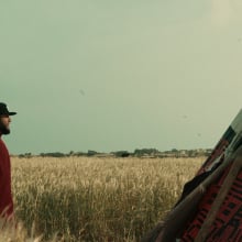 Mo Amer stands in a field beside a tent in the show "Mo."