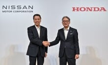 Makoto Uchida (L), president and CEO of Japanese auto maker Nissan, shakes hands with Toshihiro Mibe (R), director, president and representative executive officer of auto maker Honda