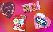 several packages of valentine's day candy including lindt truffles, yumearth lolipops and nerd clusters on a pink and orange background