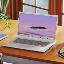 the asus chromebook plus cx34 on a wooden desk in front of a window next to a notebook, a water bottle, and a pair of glasses