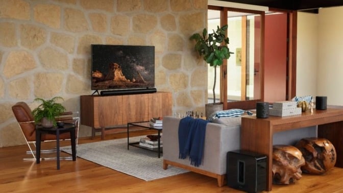 the sonos arc soundbar sits below a TV in a living room with a mountain, woodsy vibe