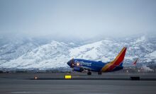 a southwest airplane take off from the runway with snow-capped mountains in the background