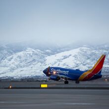 a southwest airplane take off from the runway with snow-capped mountains in the background