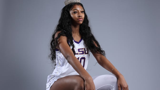 Angel Reese sits for a portrait while wearing white and purple LSU jersey and a crown 