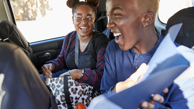 Two people riding in back seat of car and laughing