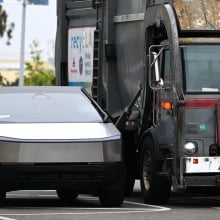 A Cybertruck parked next to a garbage truck