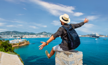 man with his hands in the air looking at the sea