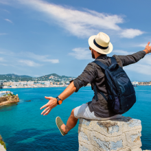 man with his hands in the air looking at the sea