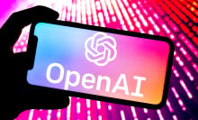 OpenAI logo open on a phone bathed in pink light. 