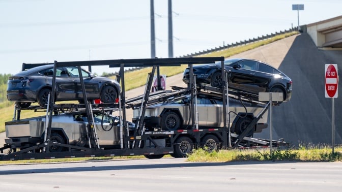 Tesla vehicles, including Cybertrucks, loaded on a transport that seems to be going nowhere.