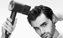 man drying his hair with dyson supersonic origin